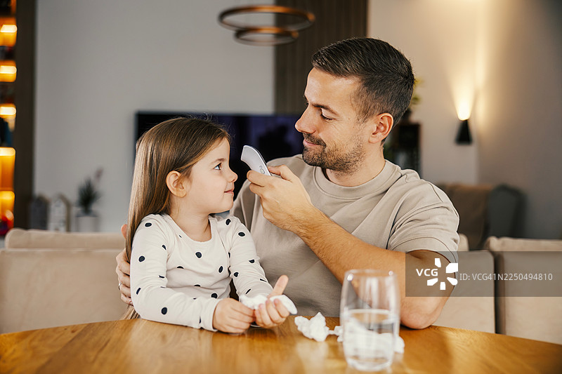 父亲用非接触式体温计为女儿测量体温图片素材
