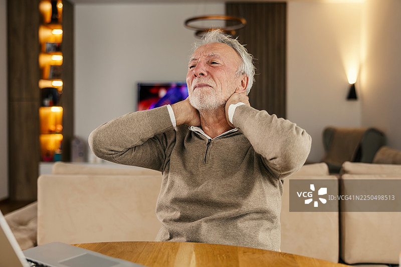 一位年长男性在家工作时感到颈部疼痛图片素材