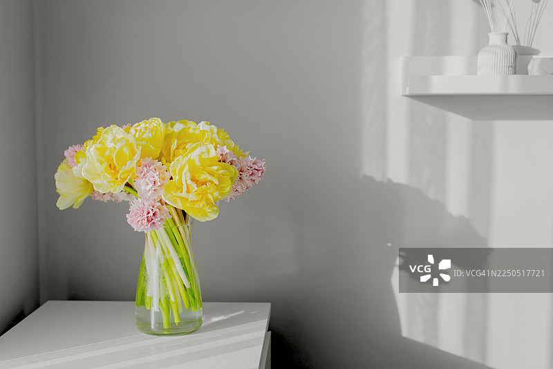 花瓶里插着新鲜的黄粉色花朵，摆放在白色的桌面，沐浴在柔和的自然光下，整体风格呼应2026年度代表色“云舞”的审美。图片素材