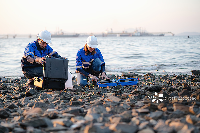 一名女子跪在岸边检查鱼类样本图片素材