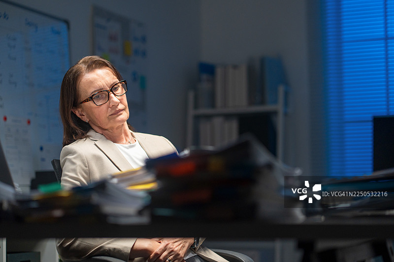 疲惫不堪的经理在深夜加班，被文件压得喘不过气，正在经历职业倦怠。图片素材