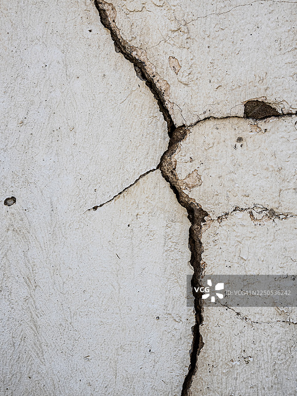 外部水泥墙，漆成白色，有裂缝、缝隙和潮湿损坏。图片素材