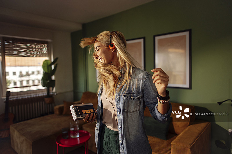 女子在家跳舞，旁边放着磁带播放器和耳机图片素材