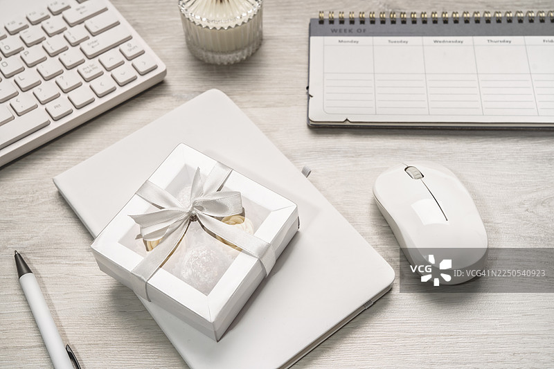 办公桌上的白色文具和时钟。装有糖果的礼品盒图片素材