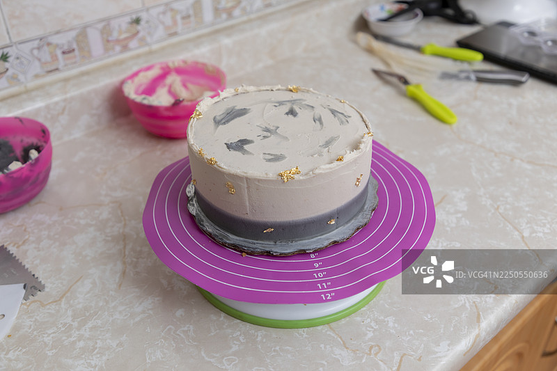 厨房里的蛋糕装饰，一款带有金色食用闪片的奶油质感甜点，放在旋转架上图片素材