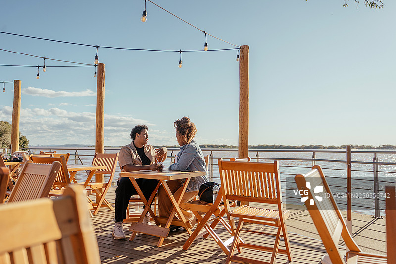 一对情侣在阿雷格里港的日落时分坐着喝巧克力图片素材