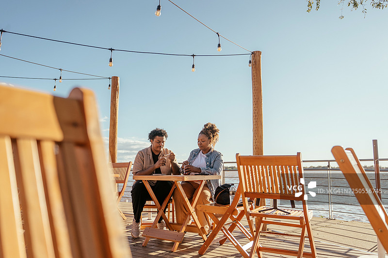 一对情侣在阿雷格里港的日落时分坐着喝巧克力图片素材
