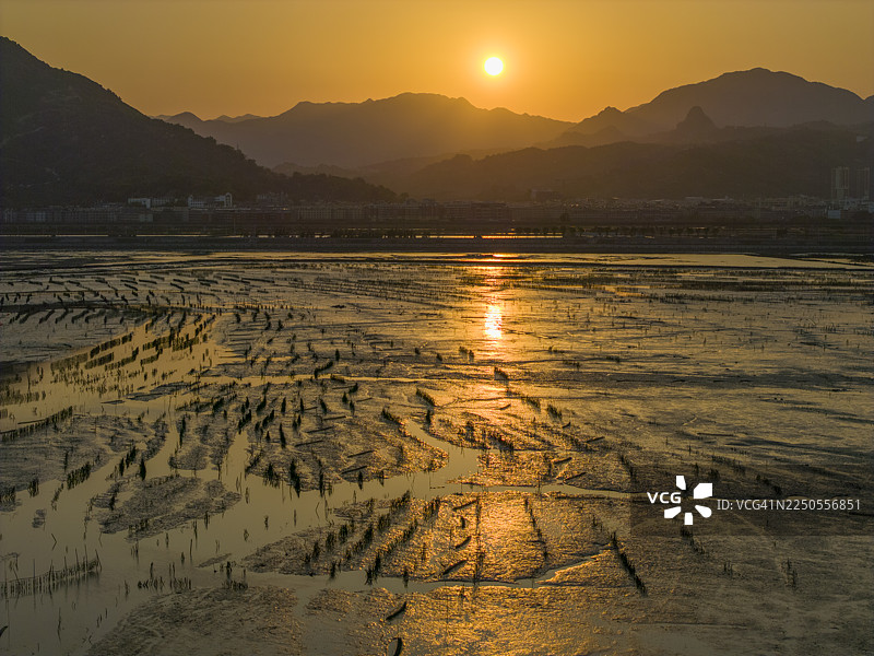 夕阳下的宁静海岸，有船只和山峦图片素材