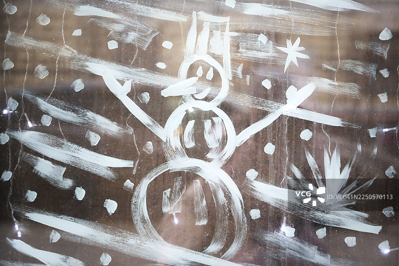 窗户上结霜的画，描绘了装饰着雪人和圣诞树的节日城市街道图片素材