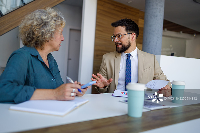 理财顾问在商务会议上与年长客户讨论投资策略，分析图表图片素材