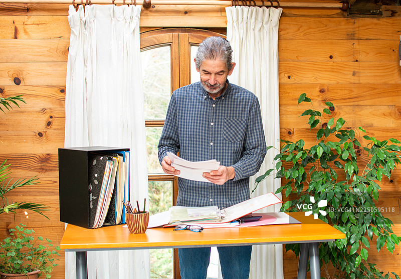 老年男子在家中办公室整理文件图片素材