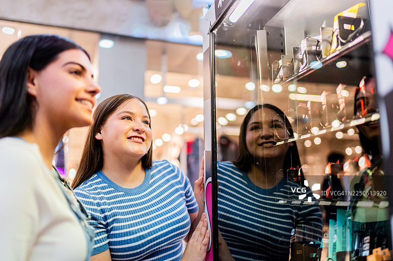 少女们在购物中心一边买自动售货机里的糖果一边聊天图片素材