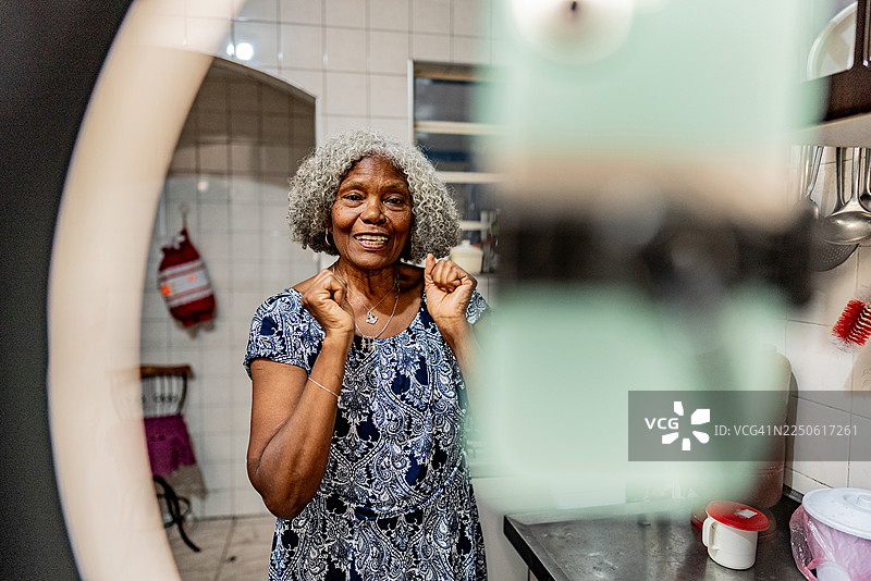 一位年长的女性在家里的厨房录制视频图片素材
