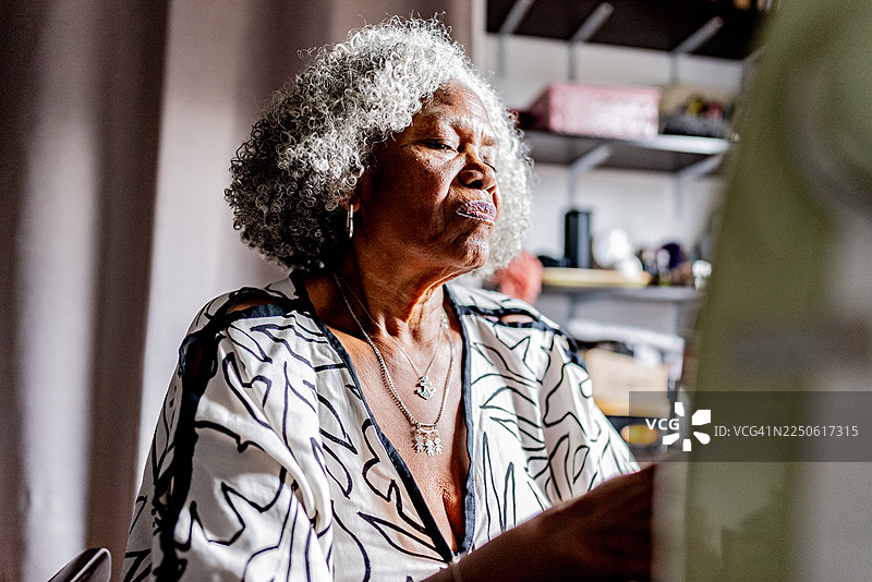 一位年长的女士在家闭着眼睛图片素材