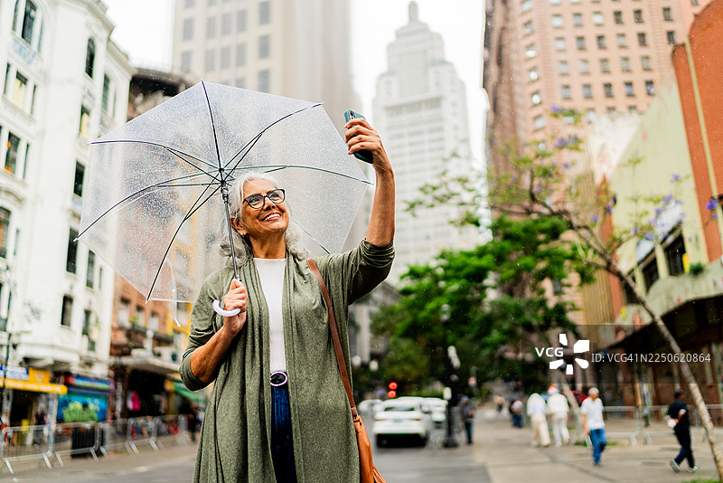 一位年长的女性在圣保罗用手机自拍或录像图片素材