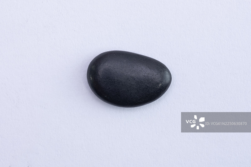 一块孤立在白色背景上的黑色石头。图片素材