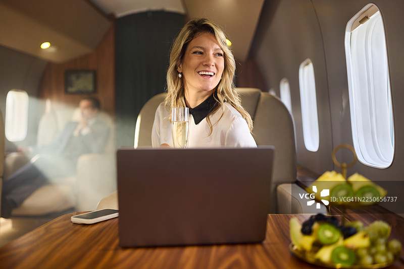 私人飞机上，快乐的女商人白天做着白日梦。图片素材