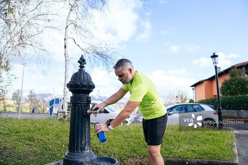 男人在公共饮水处给水瓶加水图片素材