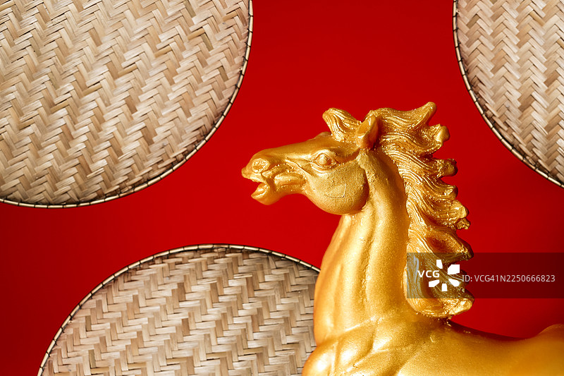 红色背景上的金色石头马雕像和竹盘图片素材