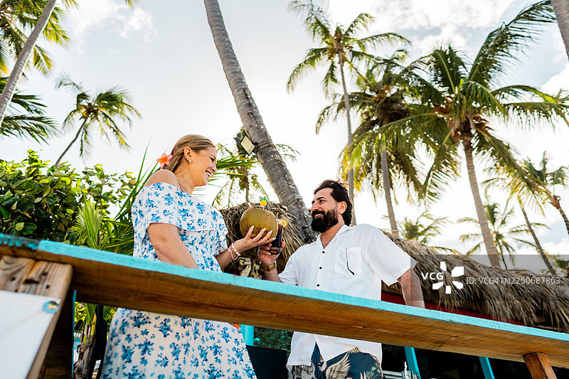 在多米尼加共和国的蓬塔卡纳海滩上，一对情侣在交谈并举杯畅饮图片素材