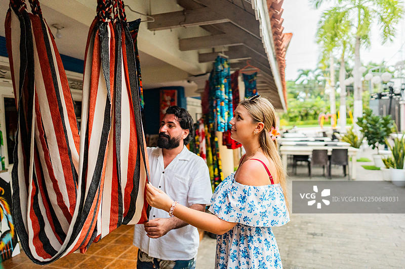 游客情侣在街头市集上挑选吊床图片素材