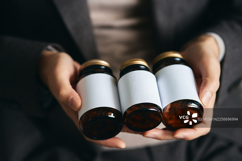 双手拿着空白瓶子，用于保健和健康补充剂图片素材