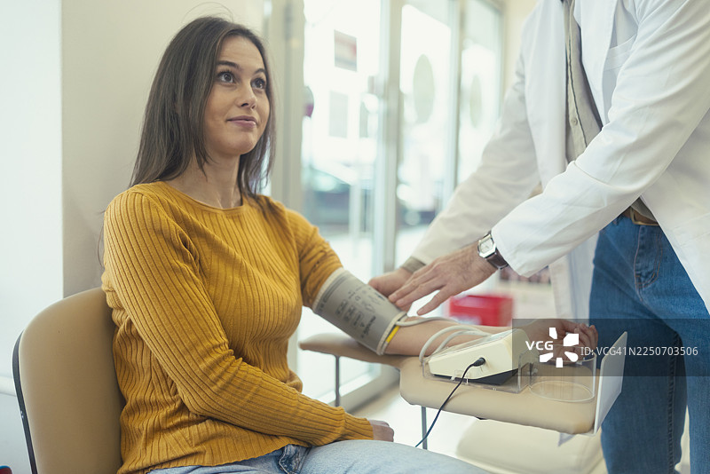 药剂师为坐着的女性患者测量血压图片素材