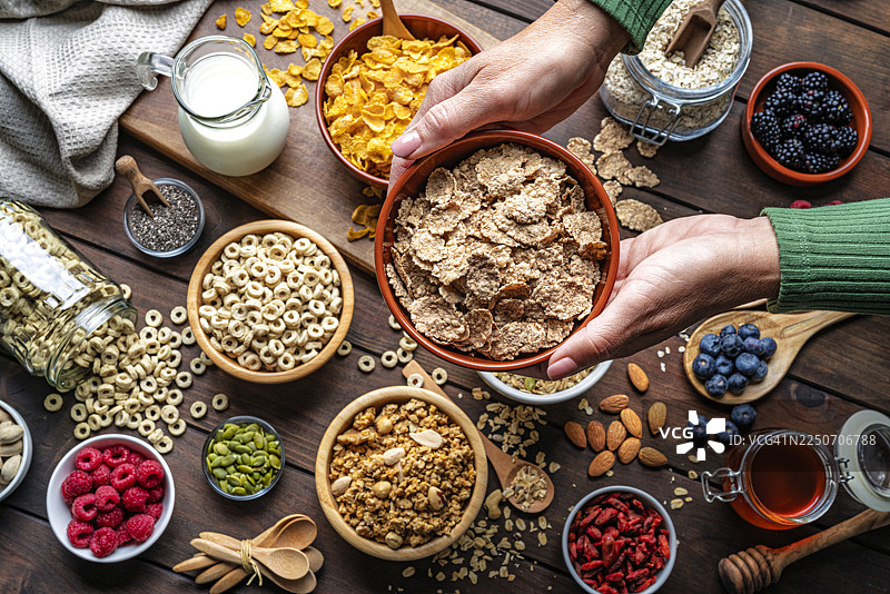 女性双手捧着一碗新鲜健康的杂粮谷物麦片，放在乡村风格的木桌上。早餐谷物、健康饮食或节食。富含膳食纤维和碳水化合物的食物图片素材