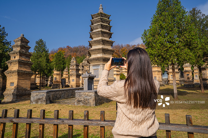 游客在寺庙森林中拍摄古塔图片素材