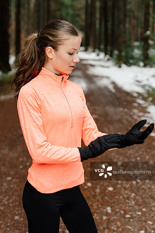 一名少女在冬季跑步前调整手套的竖构图半身照图片素材