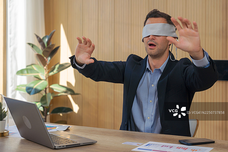 一名商人在办公室里蒙着眼睛。图片素材