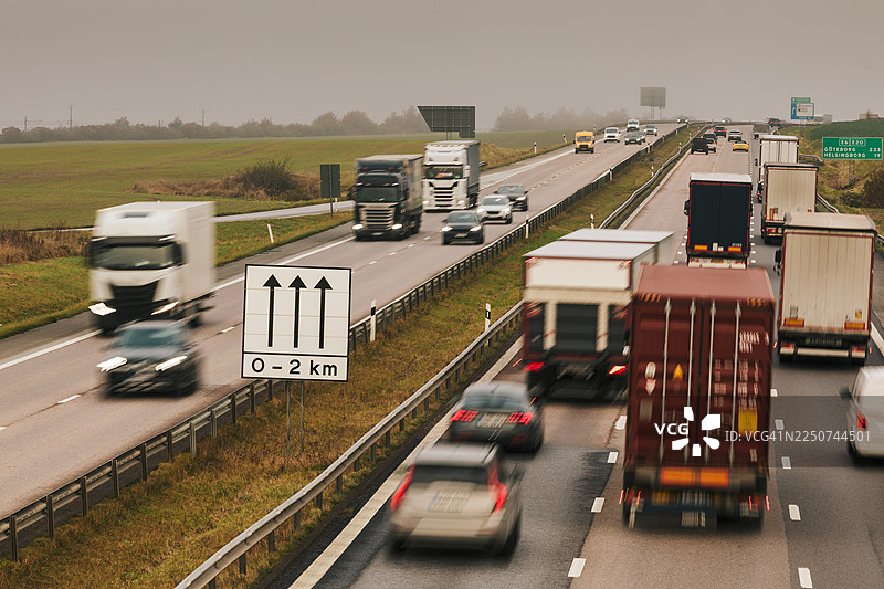 汽车和卡车在穿过农田的公路上的交通流量。图片素材