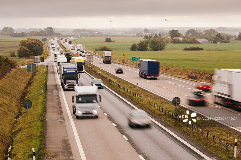 农田景观中的高速公路上的汽车和卡车交通。图片素材