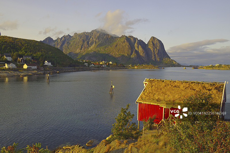 峡湾岸边的红色木屋和船只，日落时分群山环绕，罗布尔，度假住宿，雷讷，莫斯克内斯，罗弗敦，诺尔兰，挪威图片素材