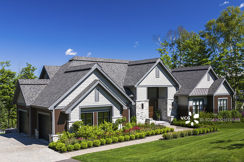 夏季，加拿大魁北克，当代天然石材、棕色染色木材和雪松瓦装饰的豪华平房风格住宅外观图片素材