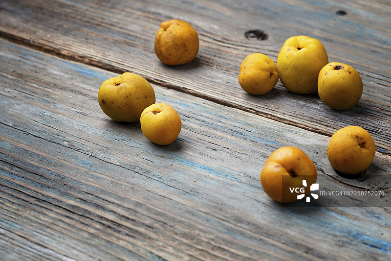 蓝色的乡村木质背景上摆放着新鲜的黄色水果。对比的概念图片素材