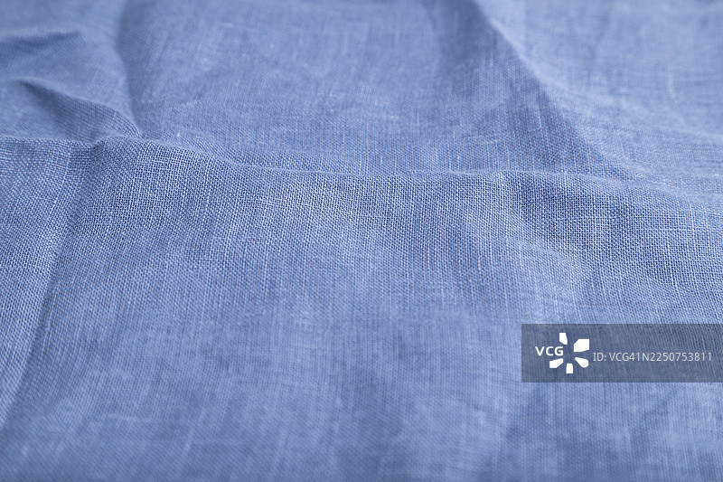 光滑蓝色亚麻纸的碎片。侧视图，天然纺织品背景和纹理图片素材