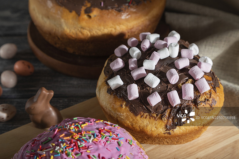 灰色木质背景和亚麻纺织品上自制的釉面复活节派，装饰有巧克力彩蛋和兔子。硬光，高对比度，侧视图，特写。图片素材