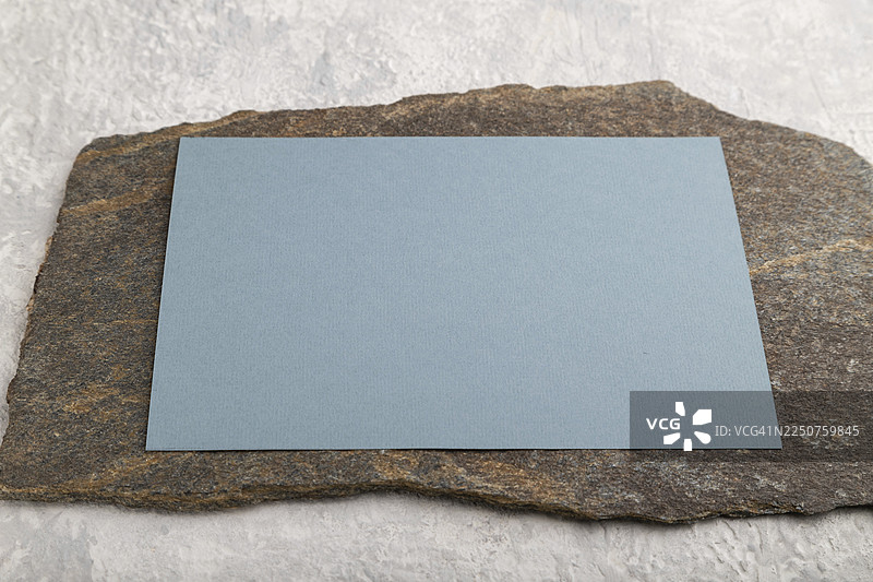 蓝色的名片，在灰色混凝土背景上带有天然石材的样机。空白，侧视图，静物，复制空间图片素材