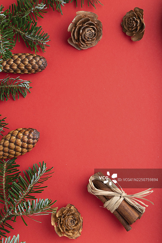 圣诞节或新年主题的构图。装饰品、盒子、肉桂、松果、冷杉和云杉的枝条、一杯咖啡，背景为红色纸张。俯视角度，留有复制空间，平面图。图片素材