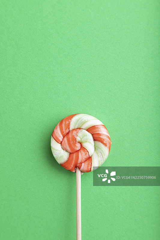 绿色粉彩背景上的单一棒棒糖，有复制空间，俯视，平面图图片素材