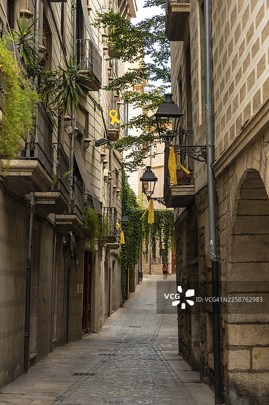 西班牙加泰罗尼亚布拉瓦海岸，赫罗纳中世纪城市，黄色元素和领带象征着对政治冲突的声援。图片素材