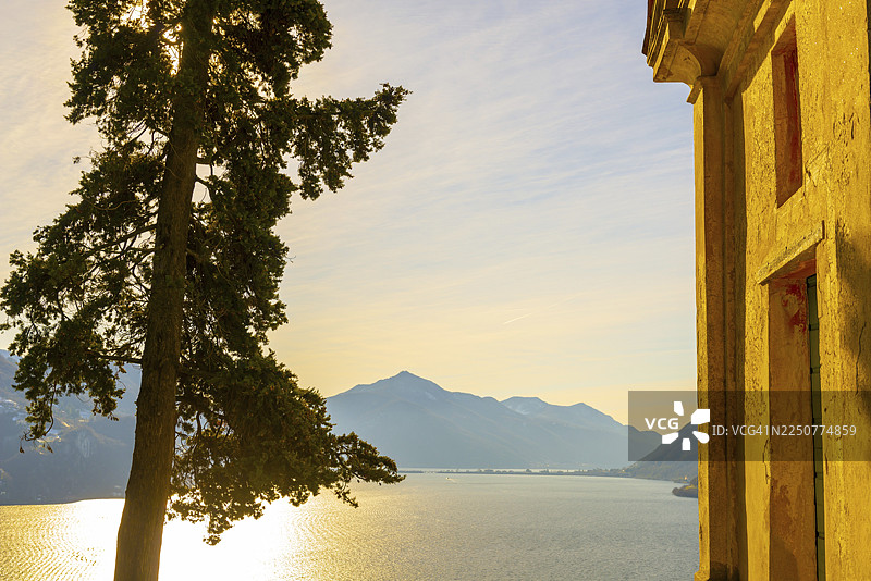 瑞士提契诺州卢加诺卡斯塔尼奥拉圣米歇尔公园的教堂、丝柏树、卢加诺湖、远山与蓝天图片素材