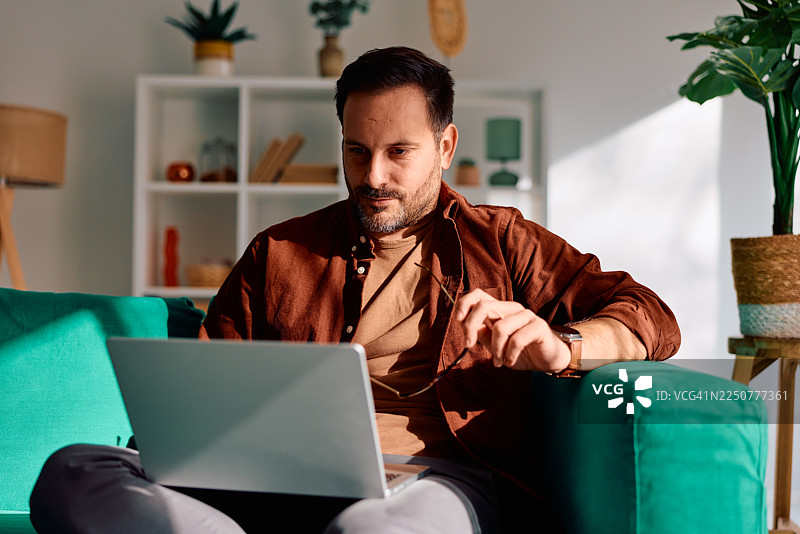 男人在家工作，坐在沙发上图片素材