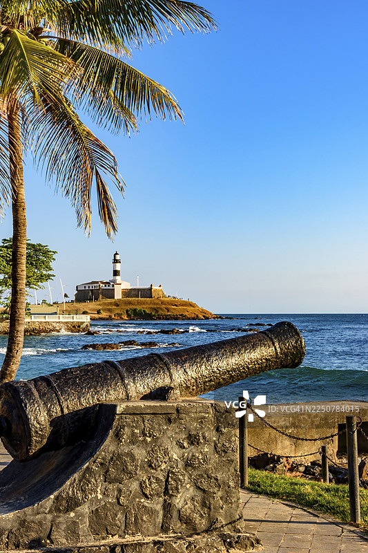 巴西巴伊亚州萨尔瓦多市防御工事中的老式帝国时期大炮，背景为巴拉灯塔和大海图片素材