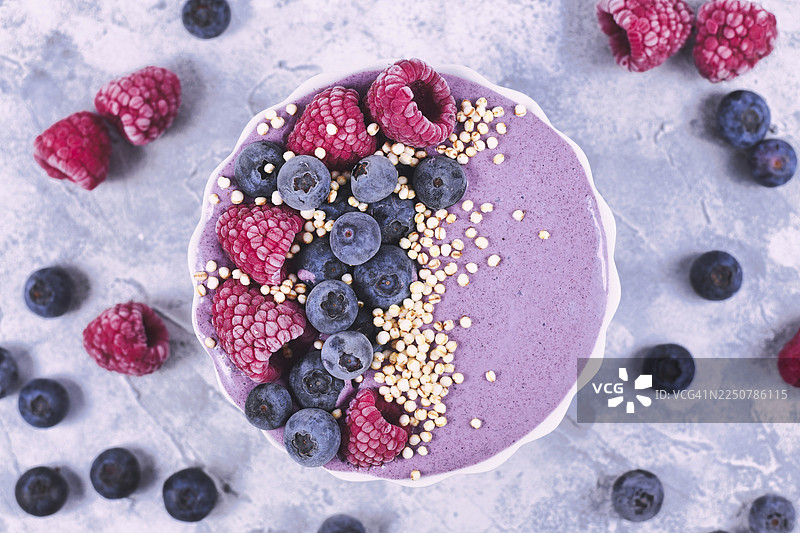 健康酸奶水果思慕雪碗俯视图，装饰有覆盆子、蓝莓和膨化藜麦图片素材