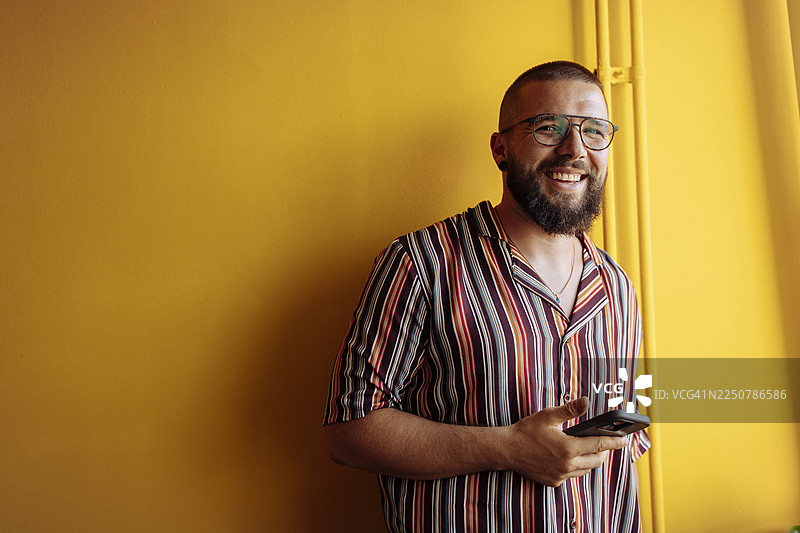 穿着条纹衫的微笑男子正在使用手机图片素材