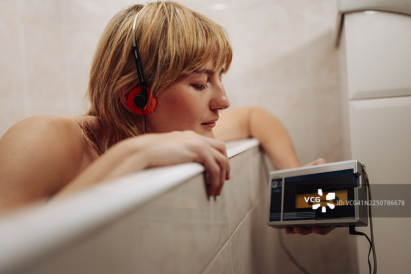 戴着耳机的女人在浴缸里听磁带播放器图片素材