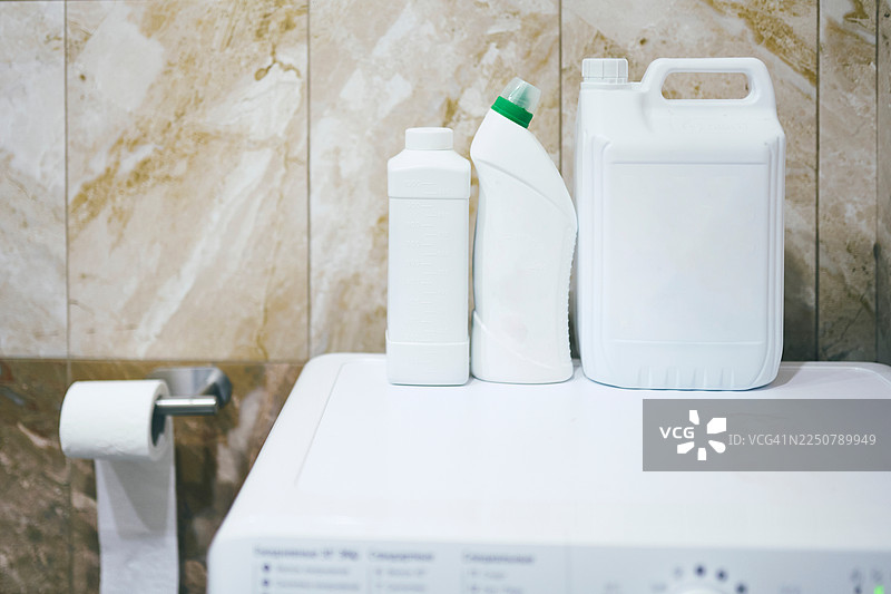 洗衣机上的洗衣房必备清洁用品，带有清洁剂瓶子图片素材