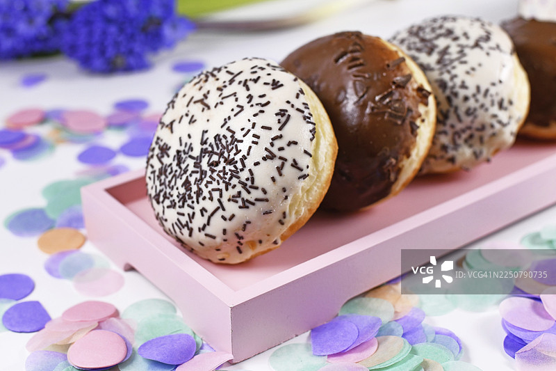 所谓的柏林甜甜圈，一种传统的德国甜点，类似于无孔甜甜圈，由甜酵母面团制成，油炸后淋上白色和棕色巧克力及糖珠图片素材
